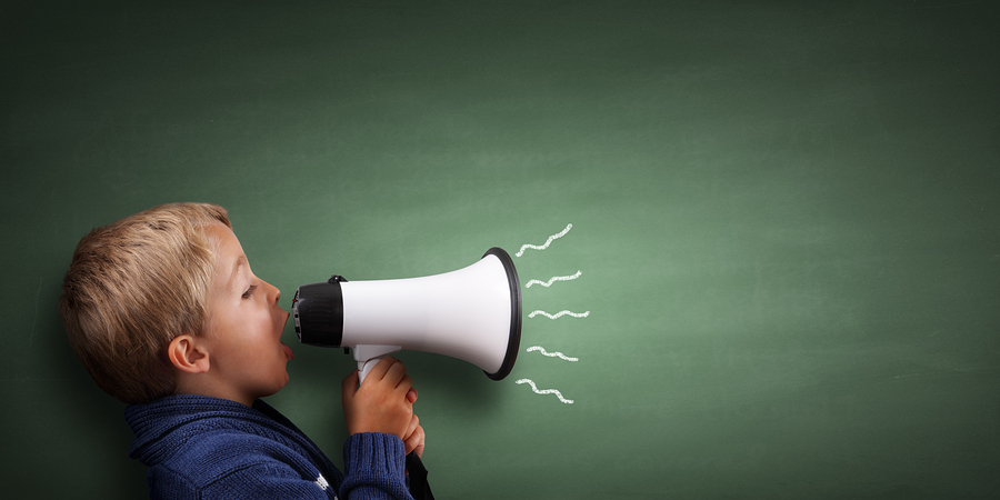 Child speaking through a megaphone against a blackboard with cop